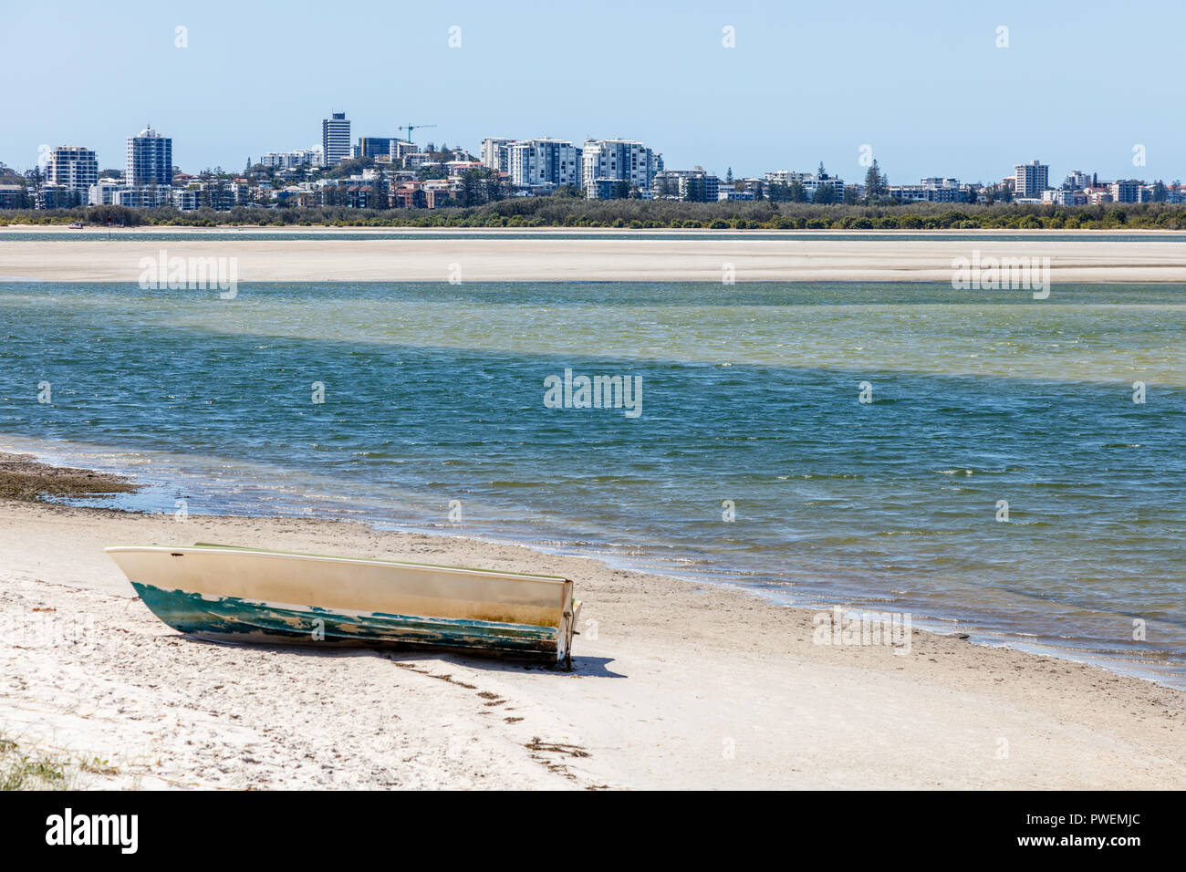 Old wooden boat sitting on the sand at Golden Beach. View of Caloundra skyline on the background. Sunshine Coast, Queensland, Australia Stock Photo