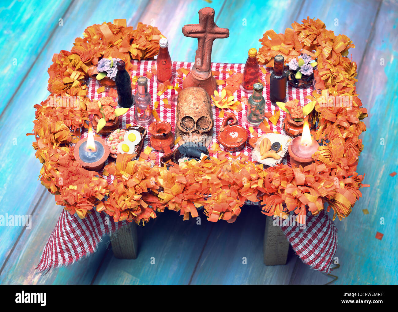 Mexican Day of the dead altar with skull, pan de muerto, drinks, cempasuchil flowers and candles Stock Photo
