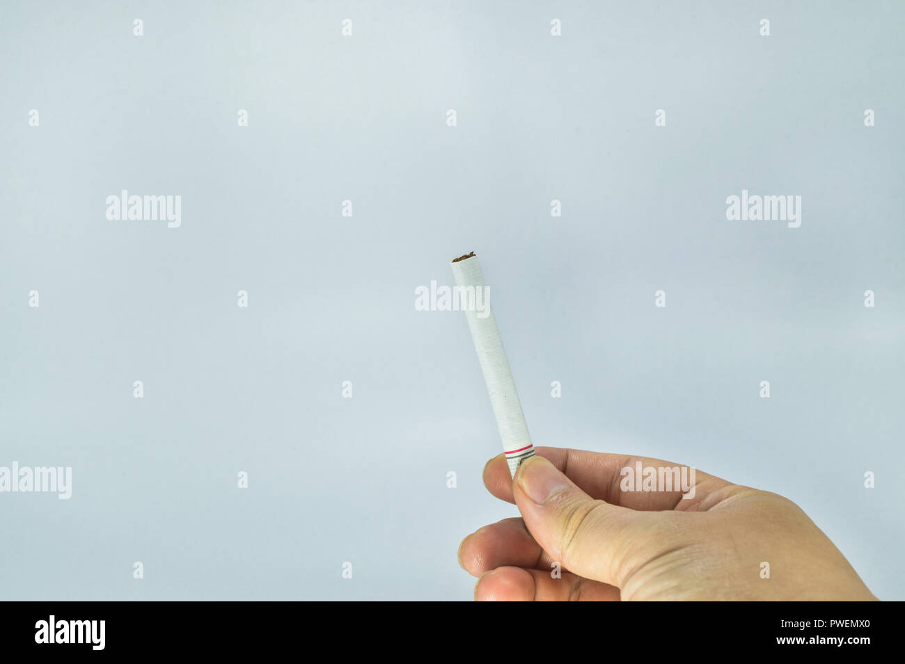 Hand holding a cigarette. Unlighted cigarette holden between two fingers. Stock Photo