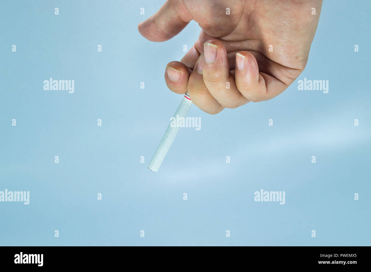 Hand holding a cigarette. Hand holding cigarette between two fingers. Stock Photo