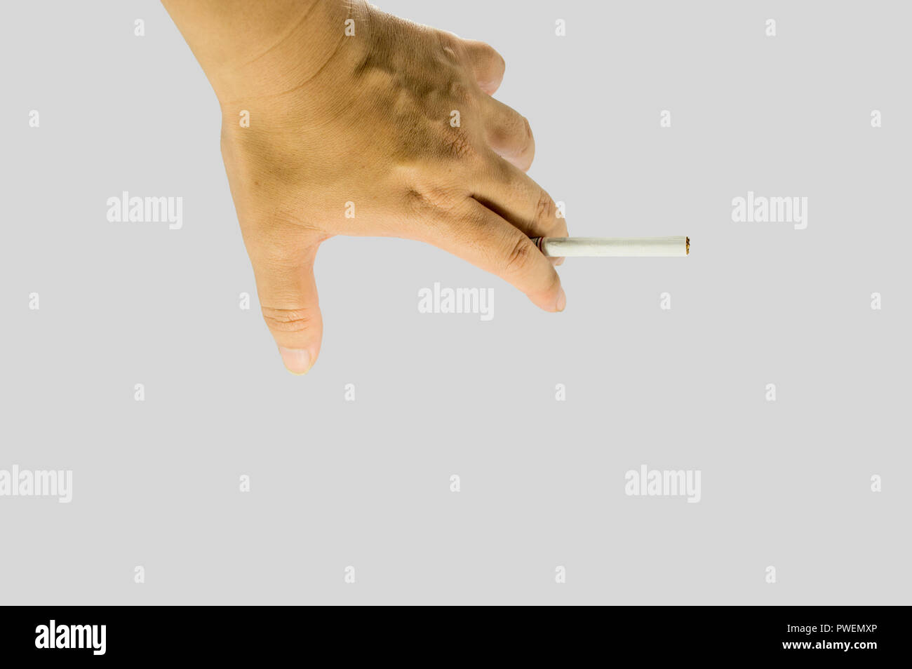 Hand holding a cigarette. Unlighted cigarette holden between two fingers. Stock Photo