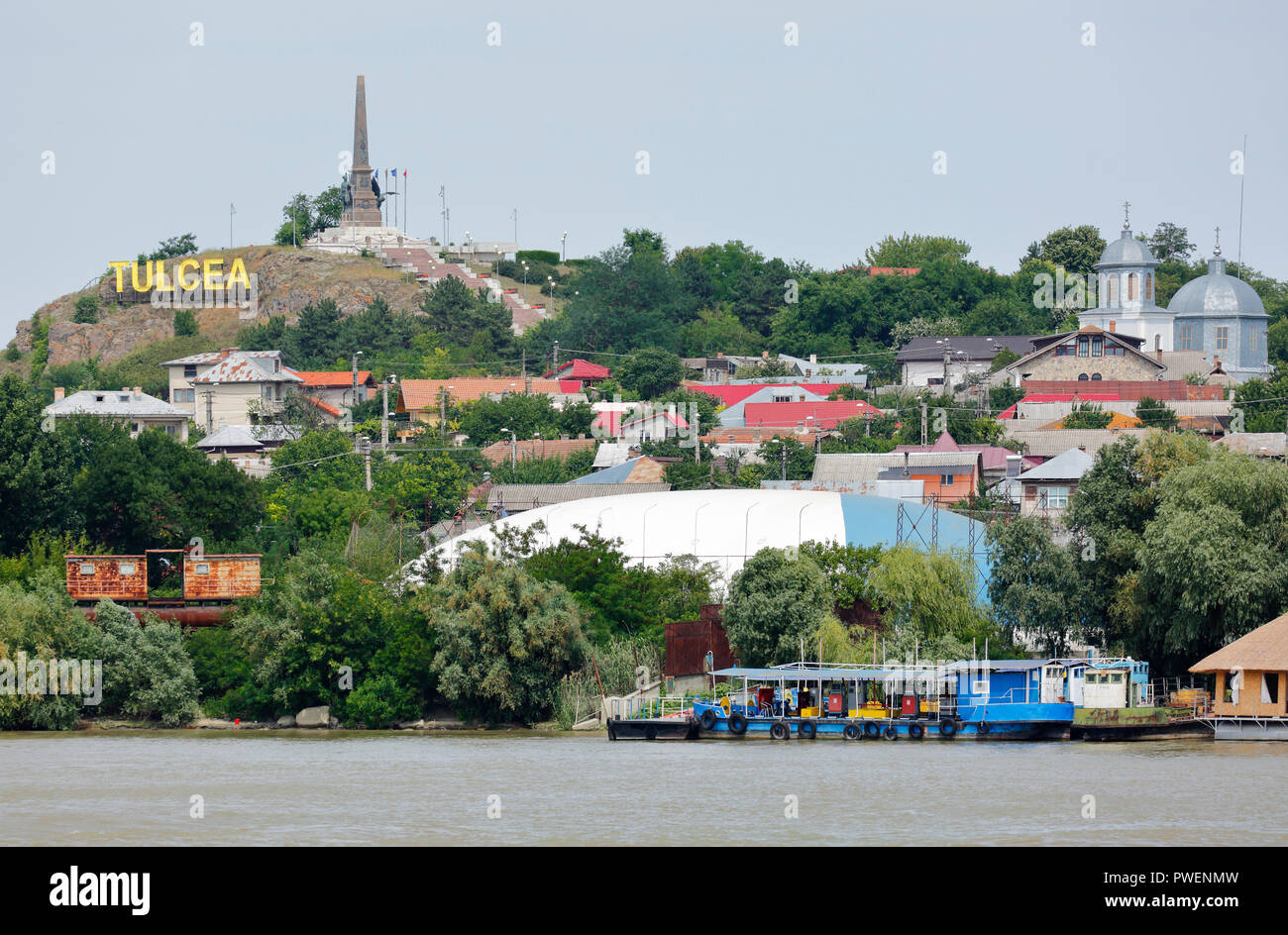 Romania, Tulcea at the Danube, Saint George branch, Tulcea County, Dobrudja, Gate to the Danube Delta, city view, harbour, independence monument on a hill, lettering Tulcea at the hill, Danube bank, river bank Stock Photo