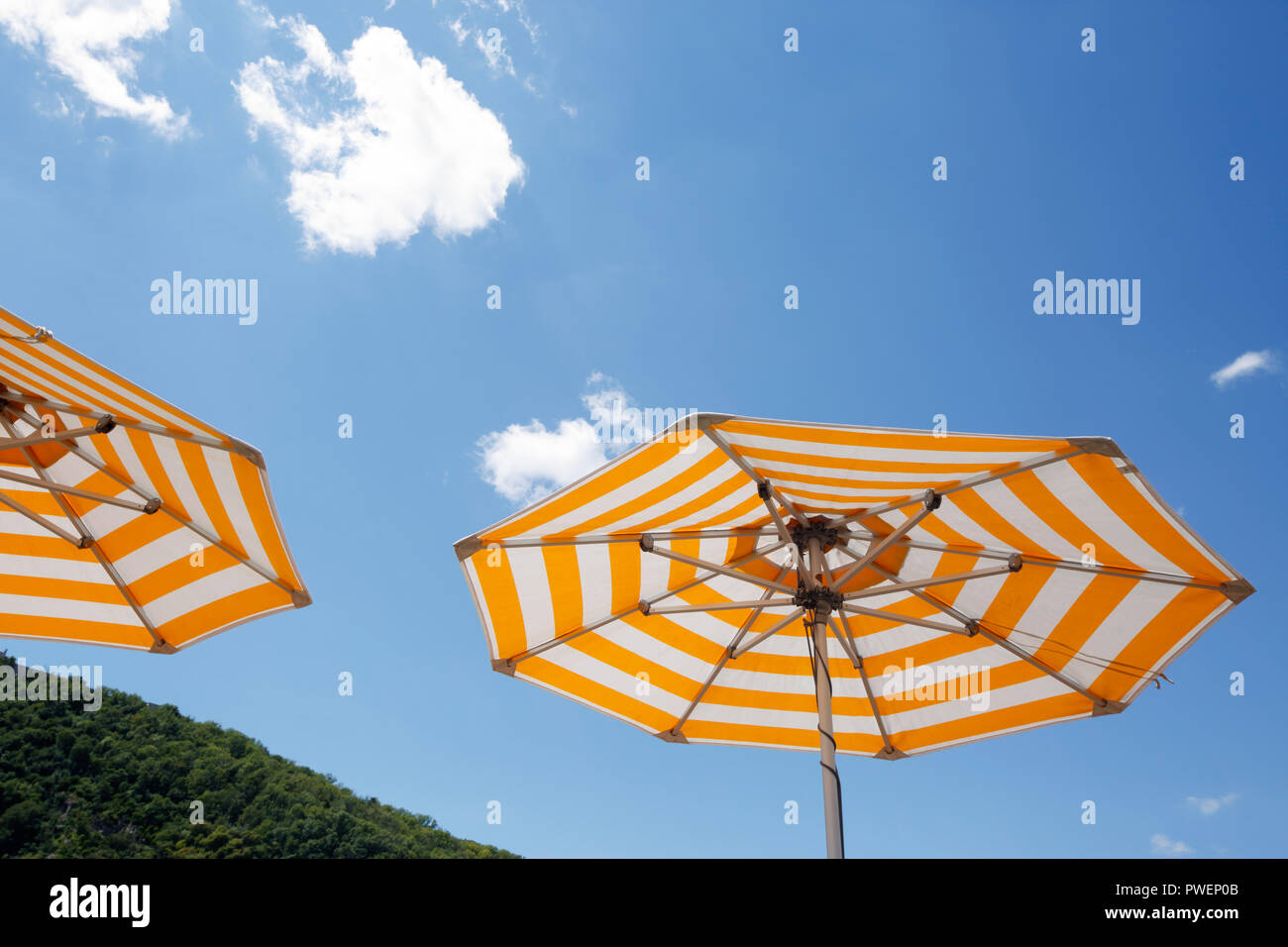 two parasols on a cruise ship against the blue sky, yellow and white, cumulus clouds, holiday, freetime, recreation, relaxation, sunlight, sunshine, shelter from sun, unpeopled, travel, cruise, tourism Stock Photo