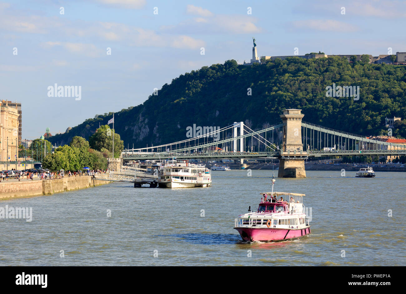Hungary, Central Hungary, Budapest, Danube, Capital City, Danube river landscape with motorboat and cruiser, behind the Istvan Szechenyi Chain Bridge and the Elisabeth Bridge between Pest and Buda, in the background the Gellert Hill with the Liberty Monument and the Liberty statue, Danube cruise, river navigation, UNESCO World Heritage Site Stock Photo