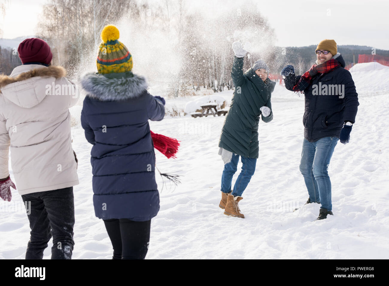 Portrait of two couples couple having fun in snow enjoying snowball fight during nice winter day outdoors on ski resort Stock Photo