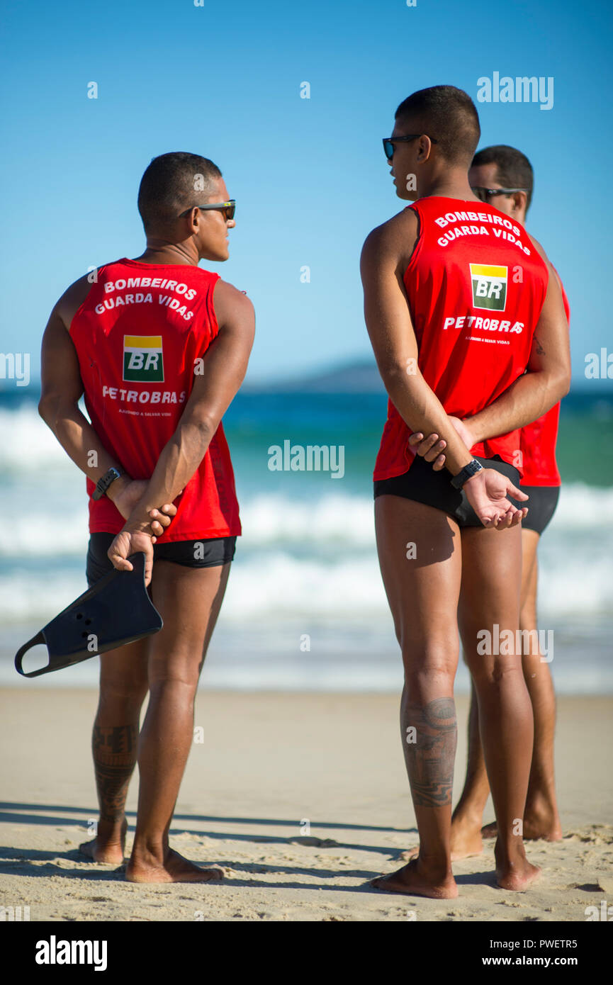 RIO DE JANEIRO - CIRCA FEBRUARY, 2018: A group of Brazilian lifeguards stand together in front of big waves on Ipanema Beach. Stock Photo