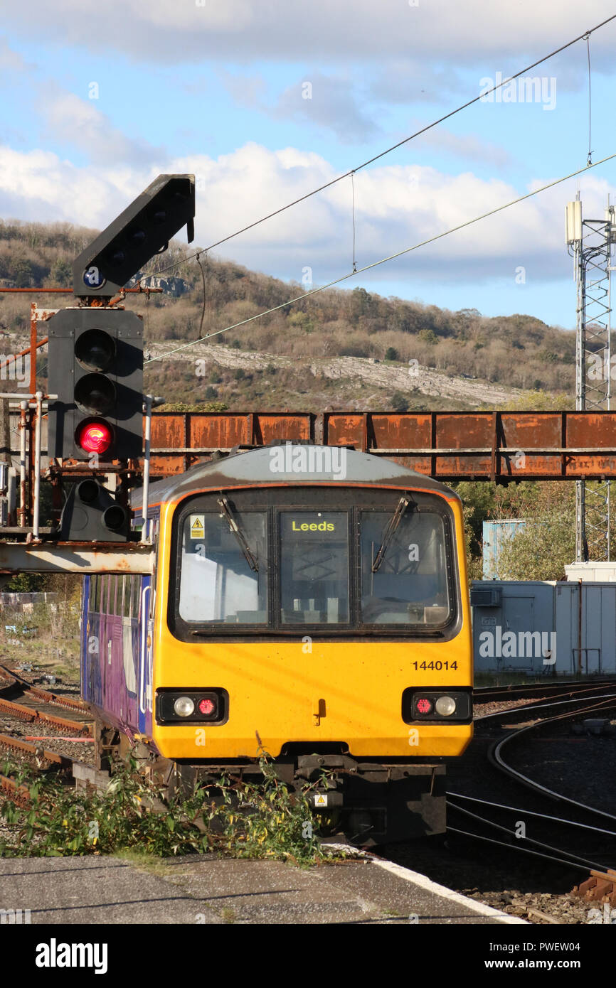 Pacer diesel multiple unit train leaving Carnforth railway station passing a color signal at the end of platform 1 as it takes the line towards Leeds. Stock Photo