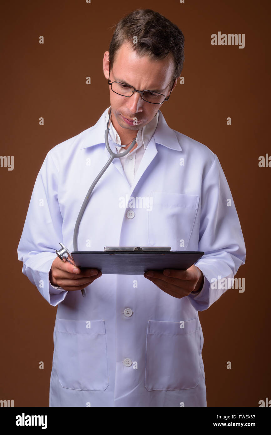 Studio shot of man doctor against brown background Stock Photo