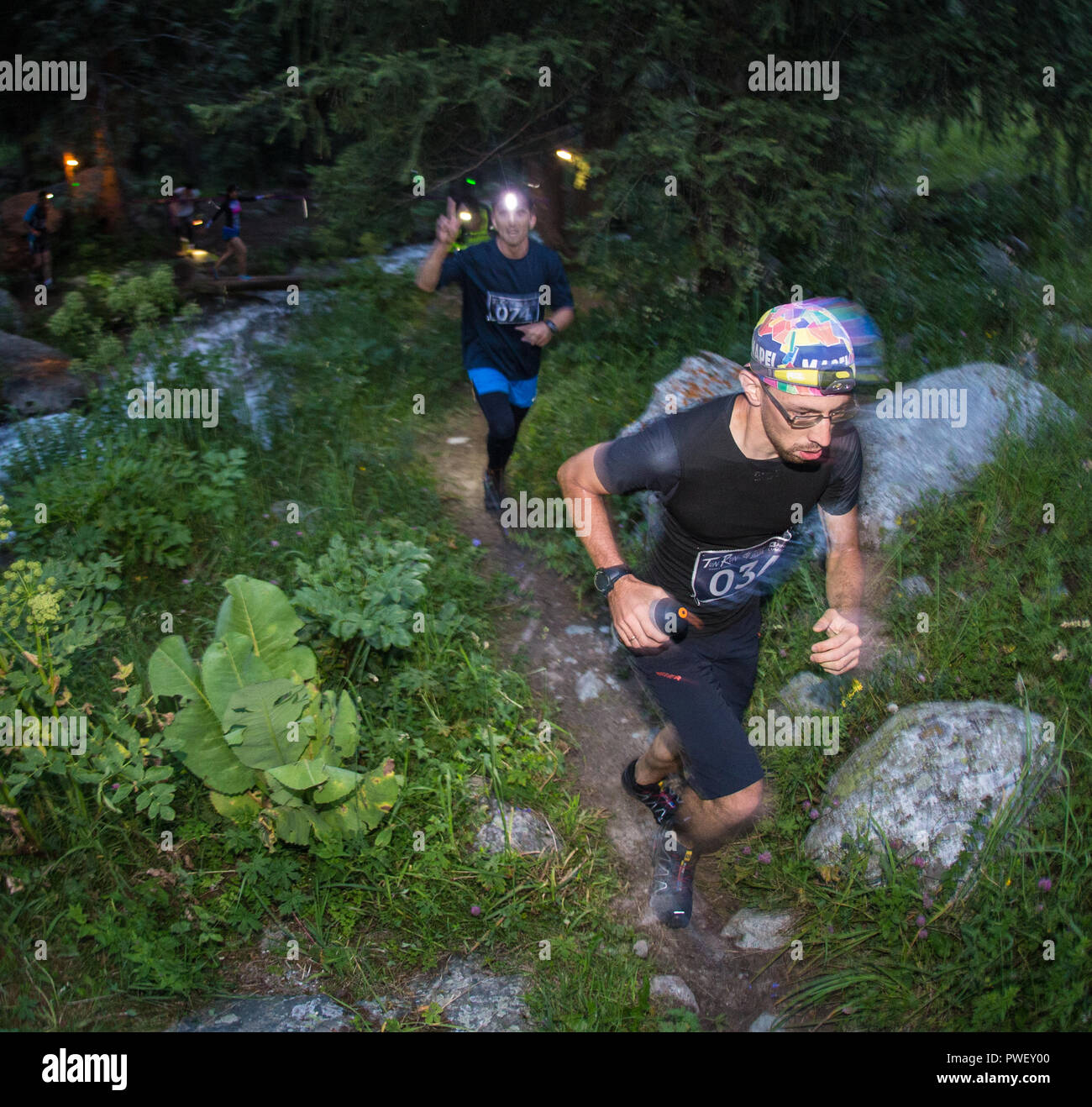 KAZAKHSTAN, ALMATY - 09 JULY 2016: Night trail running competitionsTunRun  that took place in the tract Kok Zhailau. Men and women  on a mountain road  compete with each other. Stock Photo