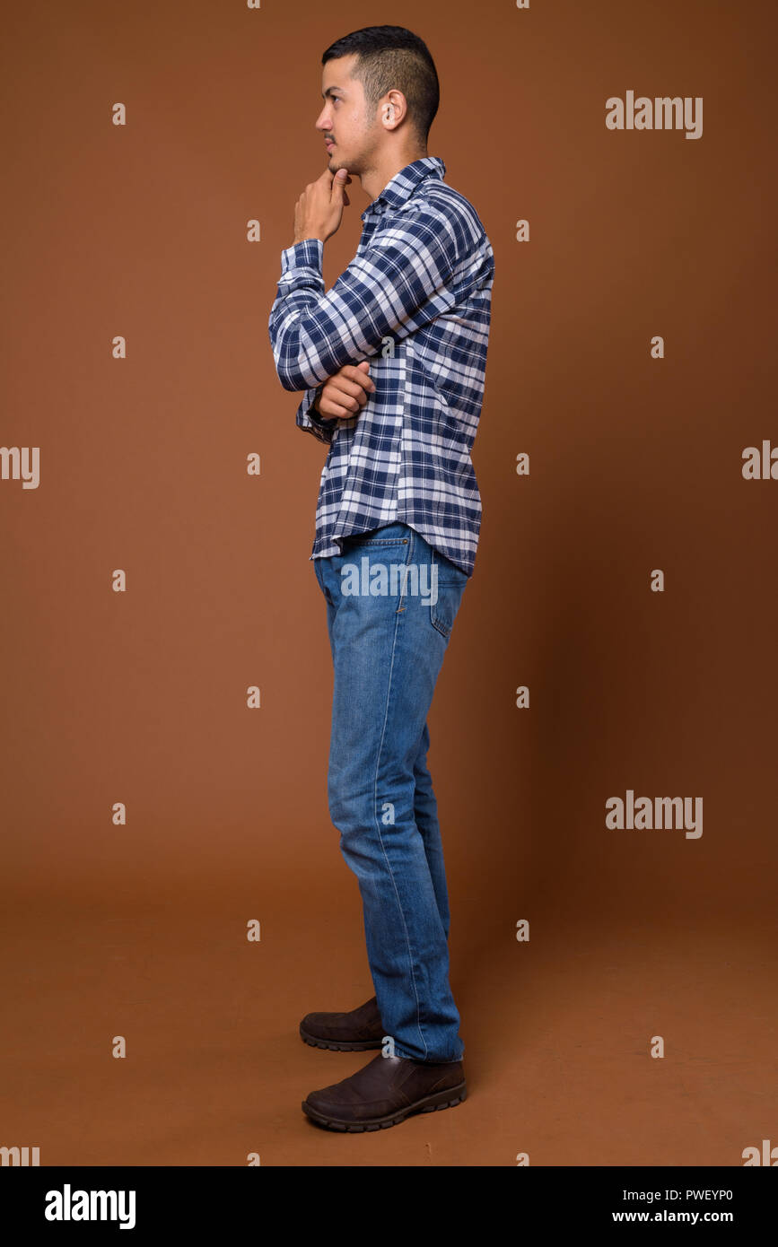 Young multi-ethnic Asian man against brown background Stock Photo