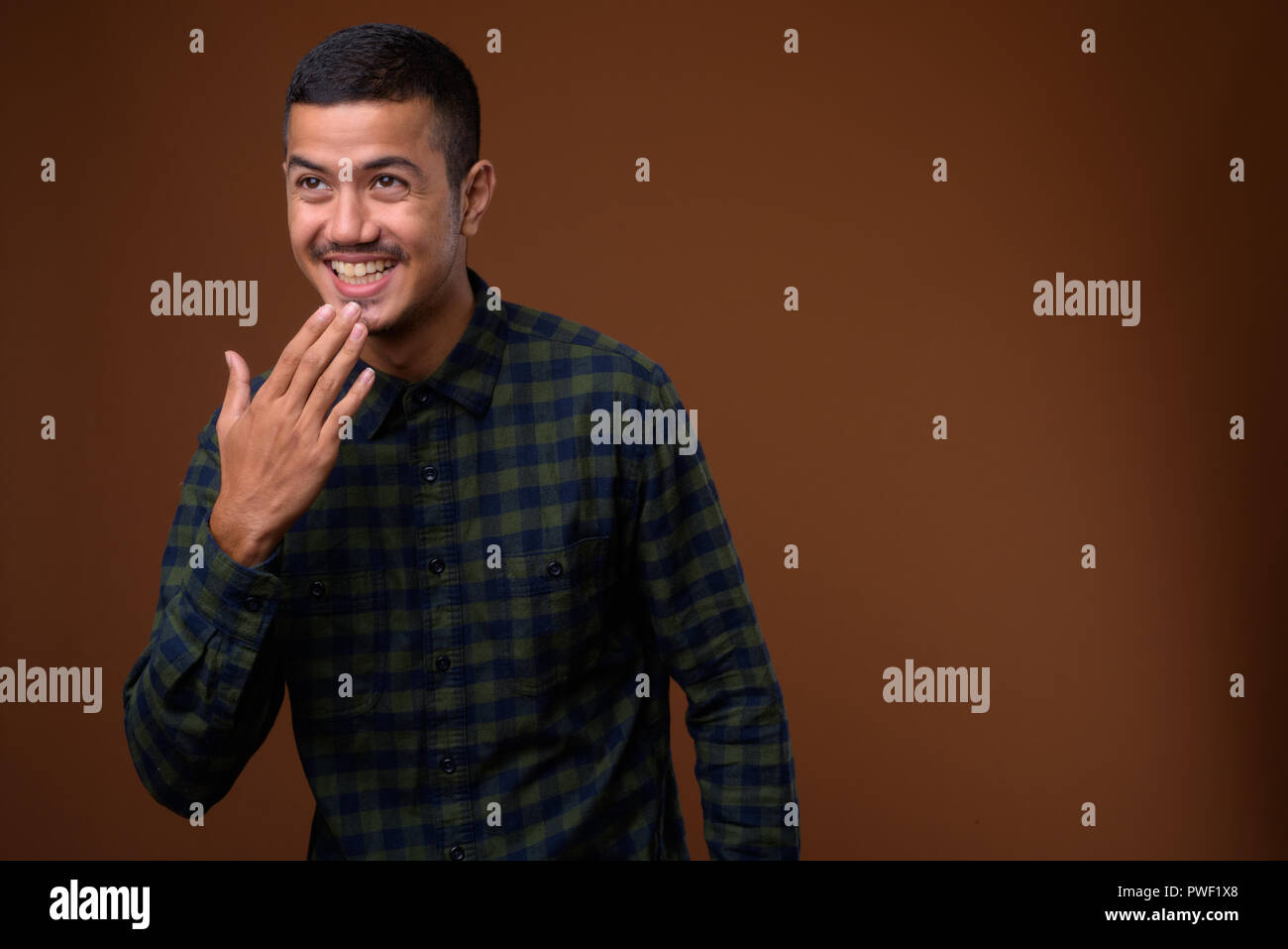 Young multi-ethnic Asian man against brown background Stock Photo