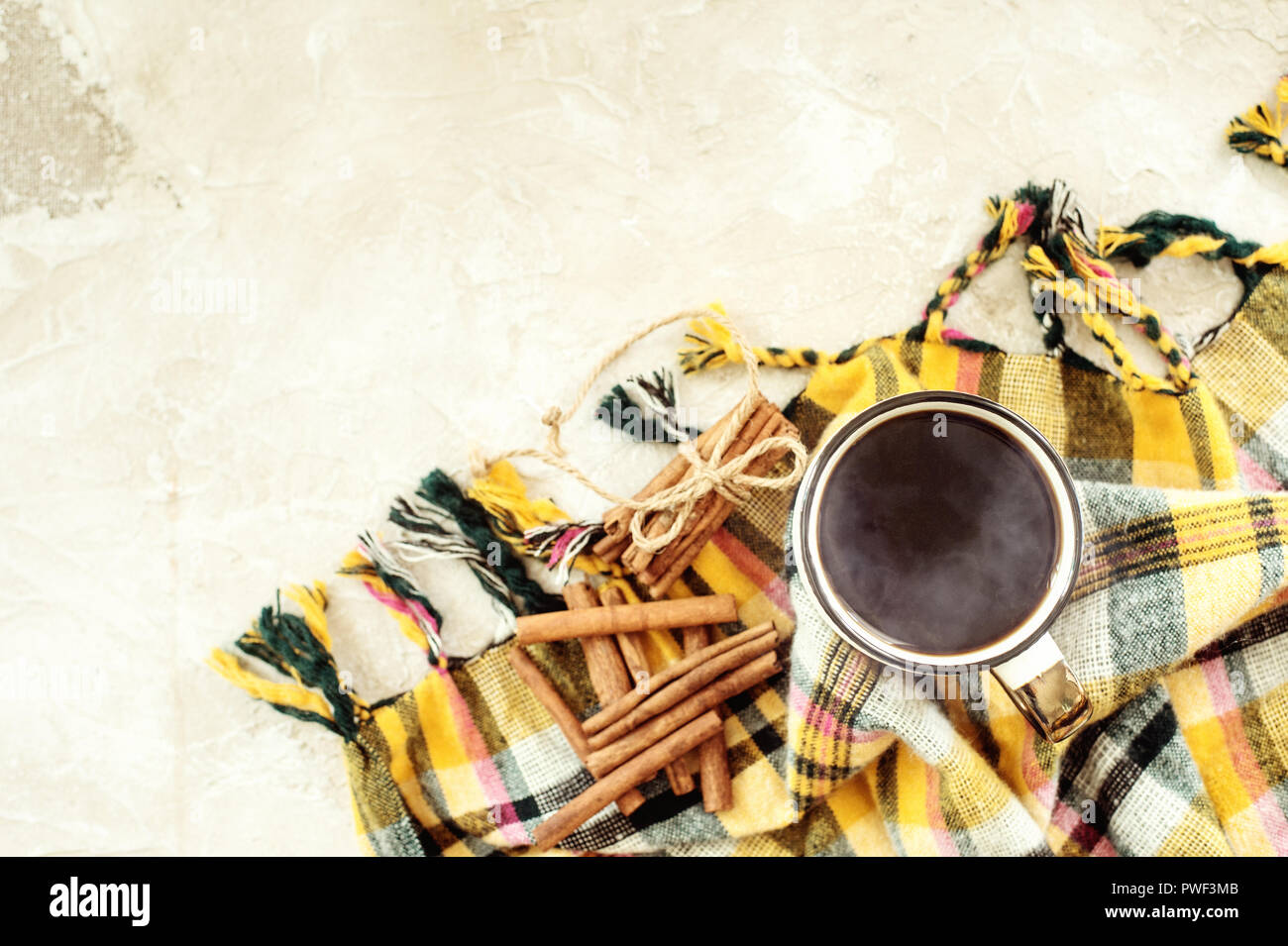 Autumn composition. Cup of coffee, blanket, autumn leaves, cinnamon sticks on beige background. Flat lay, top view. Stock Photo