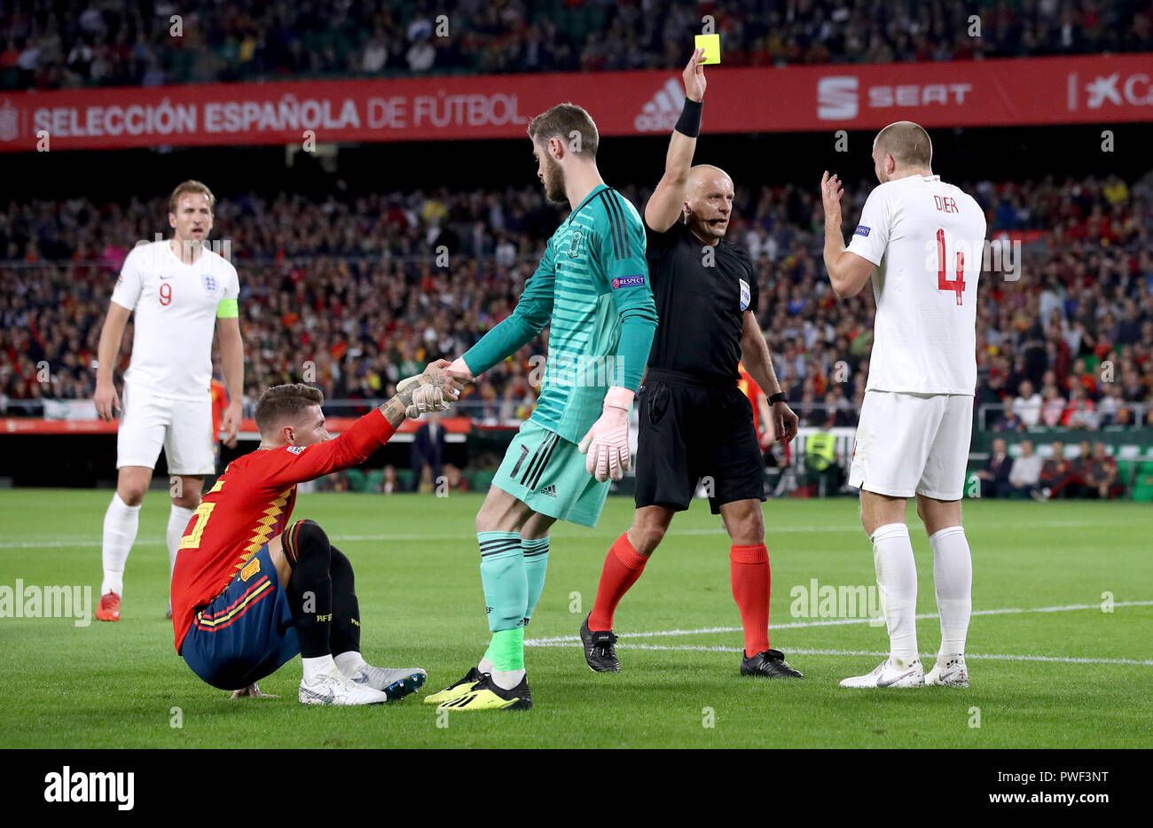 Spain's Sergio Ramos is helped to his feet as England's Eric Dier receives  a yellow card from Referee Szymon Marciniak during the Nations League match  at Benito Villamarin Stadium, Seville Stock Photo -