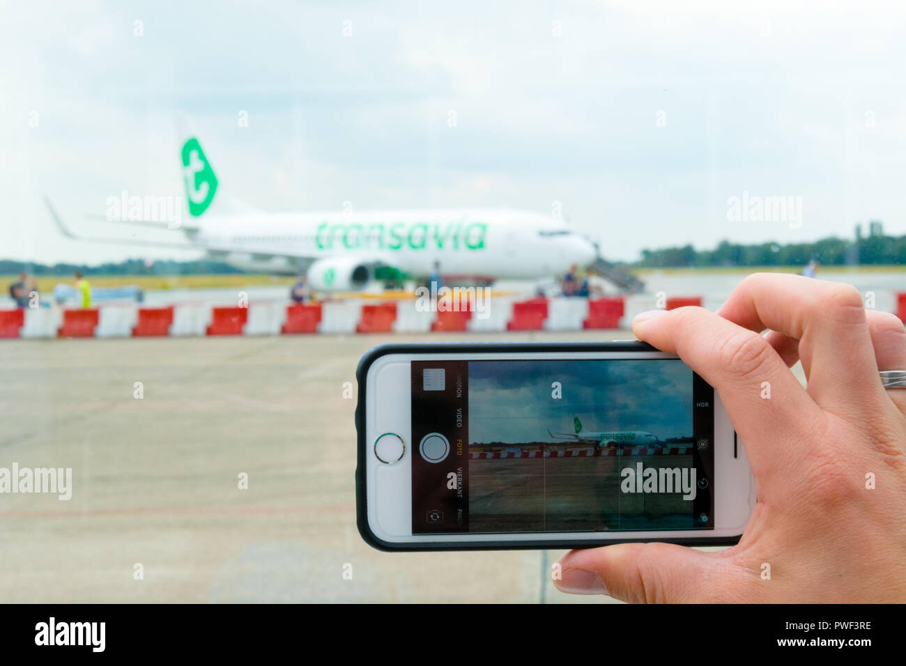 Groningen, Eelde Airport, Netherlands, August 15, 2018: View of a man's hands making photo on mobile phone of Transavia boeing 737-800 on airport Stock Photo