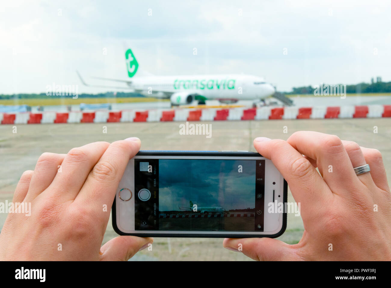 Groningen, Eelde Airport, Netherlands, August 15, 2018: View of a man's hands making photo on mobile phone of Transavia boeing 737-800 on airport Stock Photo