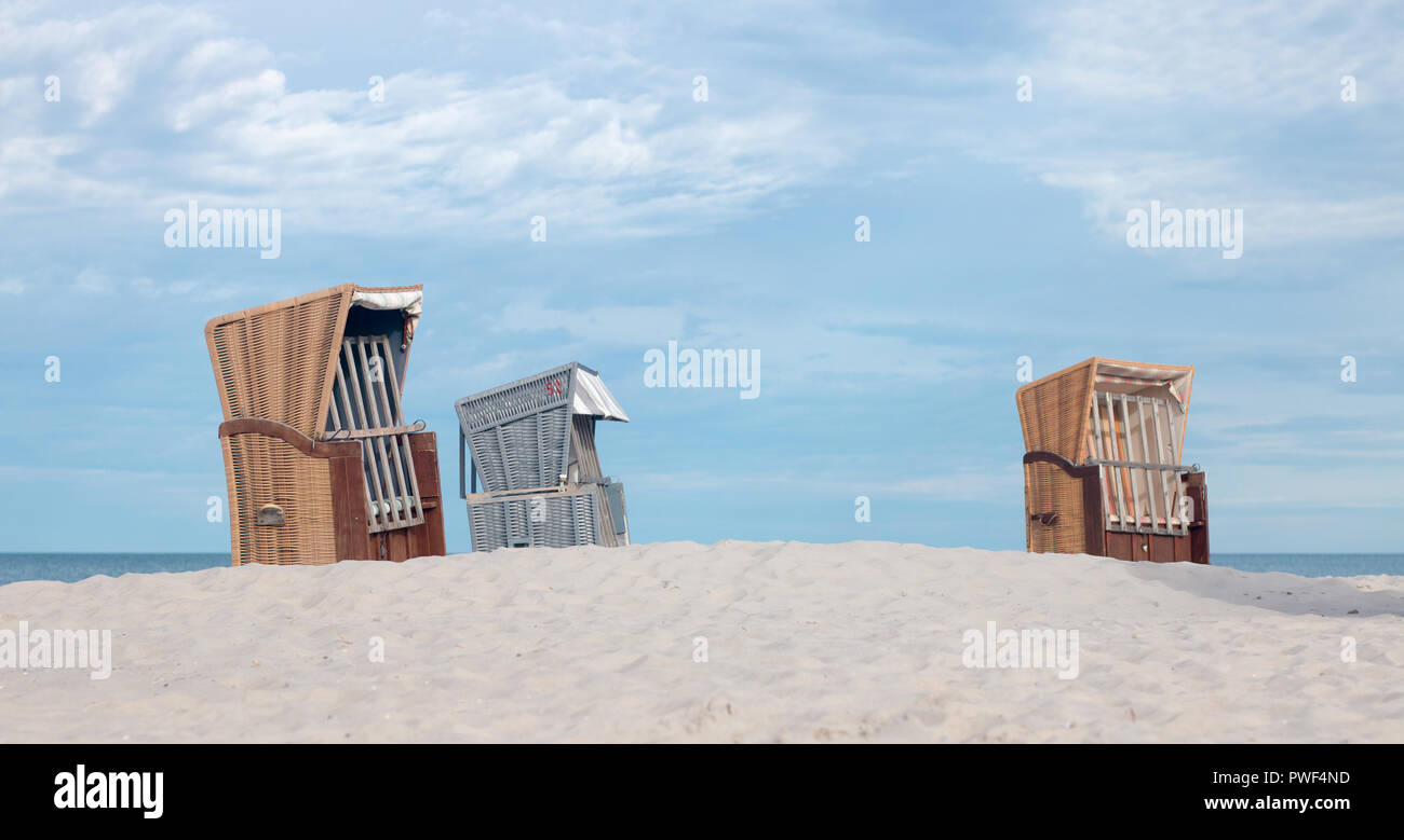 Three beach chairs stand on a sand dune at the Baltic Sea. Stock Photo