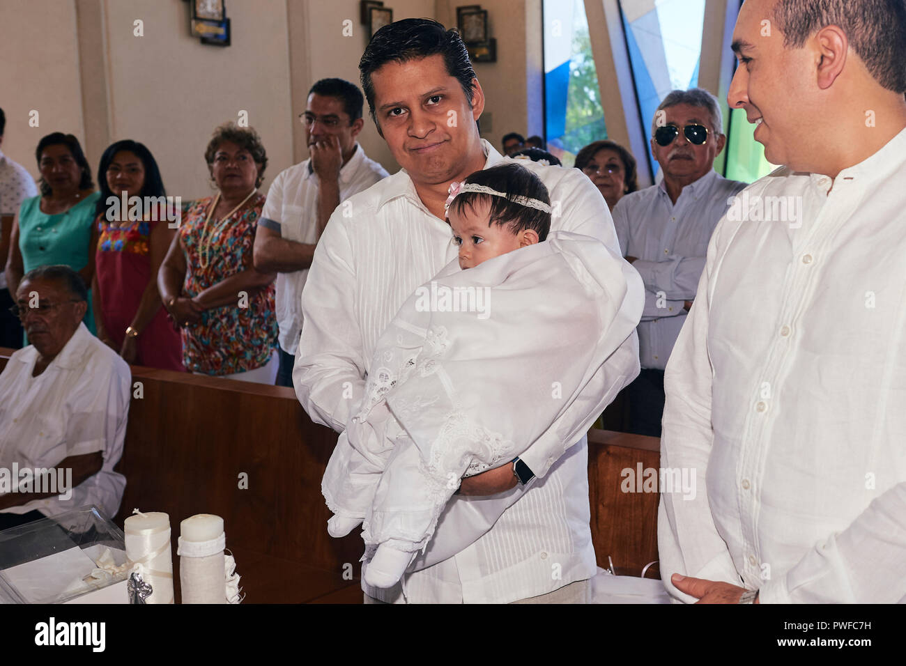 MERIDA, YUC/MEXICO - NOV 18, 2017: Godfather carries goddaughter for baptism at the catholic church Stock Photo