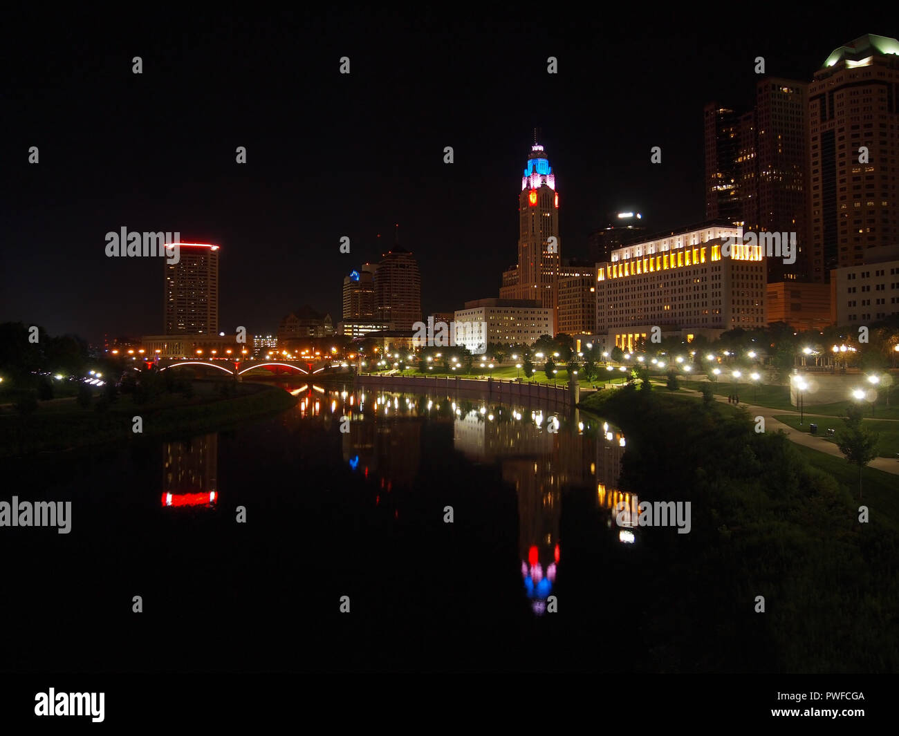 COLUMBUS, OHIO - JULY 15, 2018: Looking up the Scioto River at the skyline of Columbus, Ohio over the tree lined, grassy. lighted pathways and sidewal Stock Photo