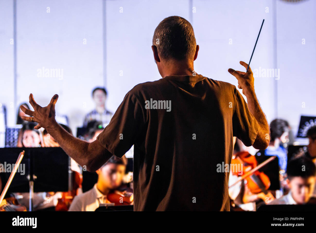 Back view of a male conductor directiing his band at a local school concert Stock Photo