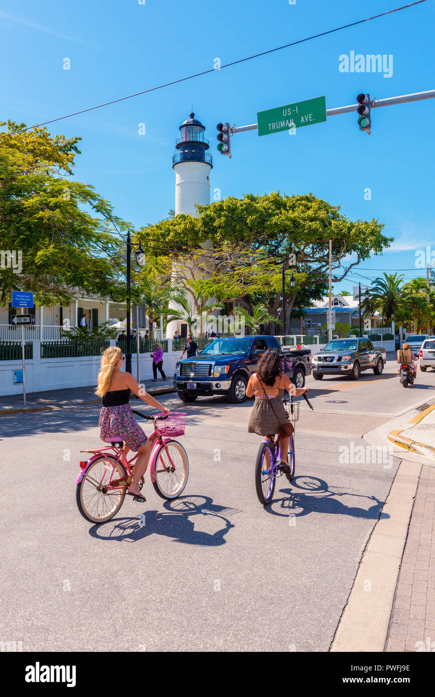 Street traffic with cars and cyclists in Key West, Florida Keys, Florida, USA. The famous Key West Lighthouse can also be seen. Stock Photo