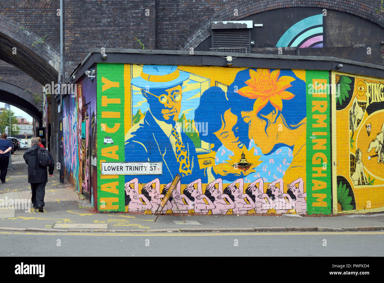 Pedestrian Walks Past Street Art in the Rundown Inner City Streets of
