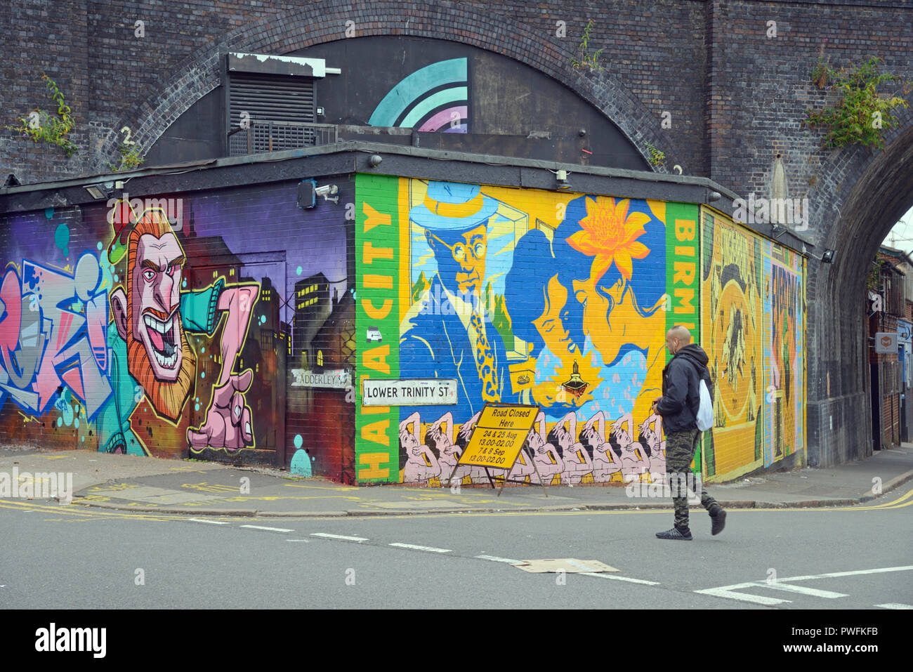 Pedestrian Walks Past Street Art in the Rundown Inner City Streets of