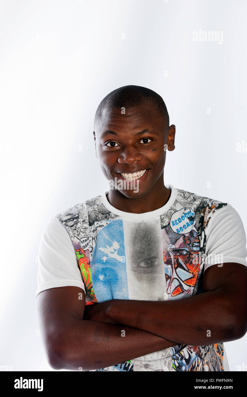 Portrait of a young african male wearing a printed colourful t-shirt smiling with arms crossed on white background Stock Photo