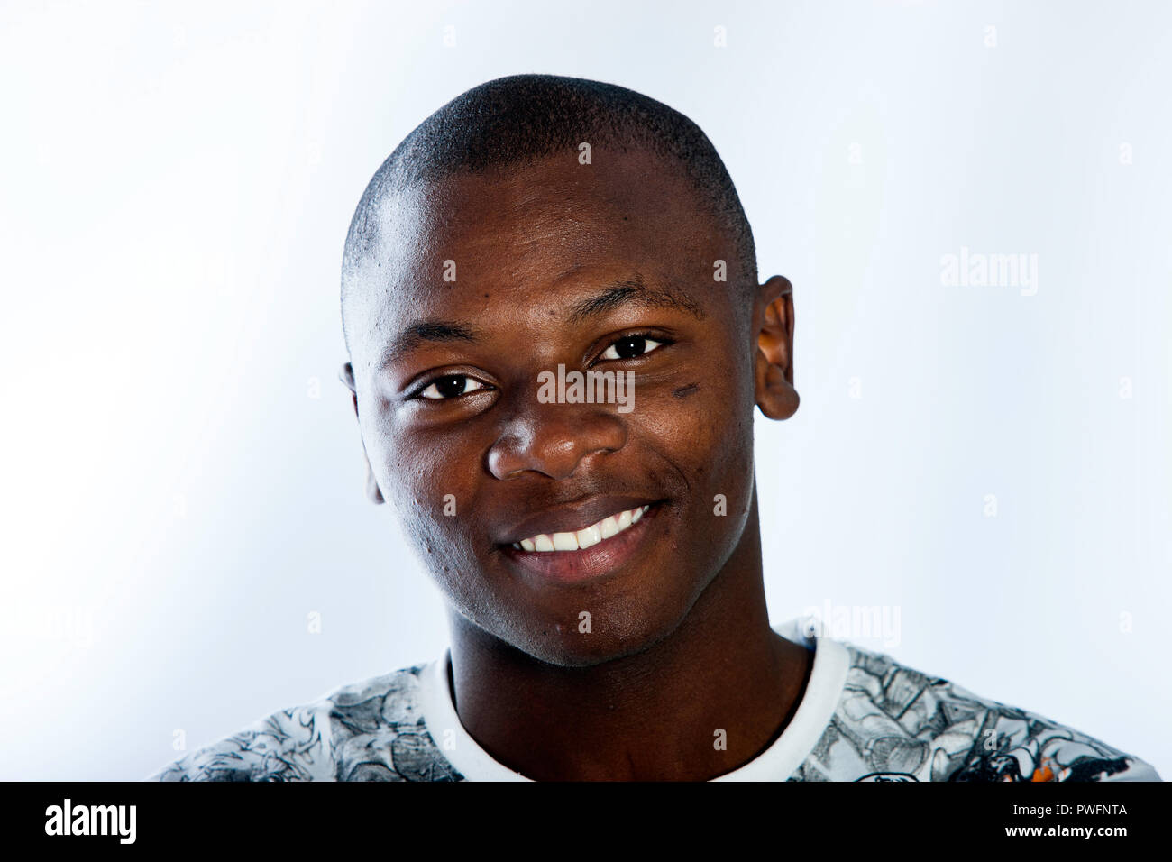 Portrait of a young african male smiling broadly on of white background looking straight in to the camera. Stock Photo