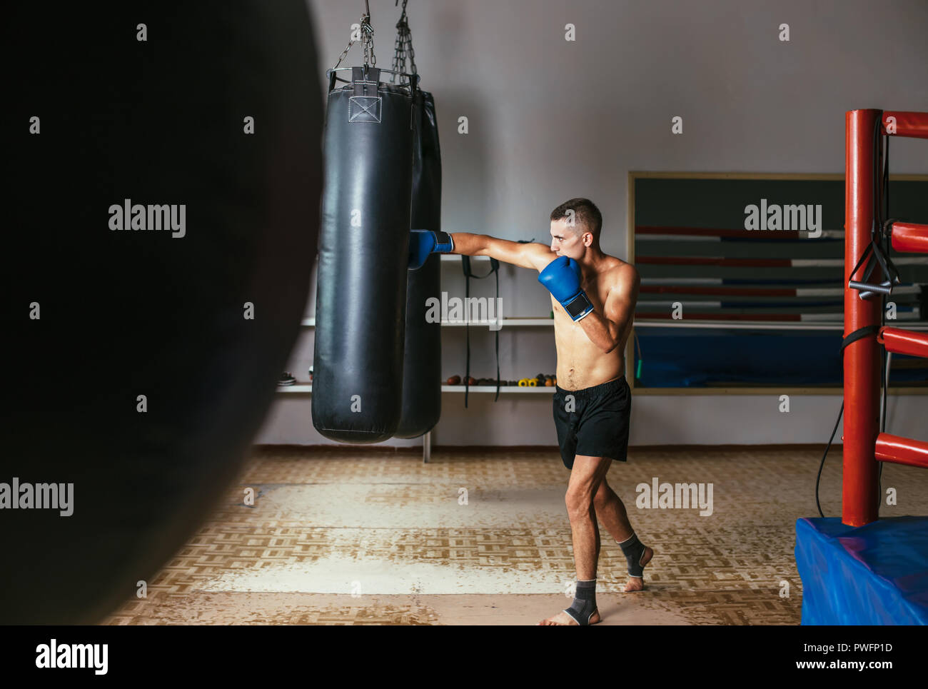 Male boxer hitting punching bag at a boxing studio. Sport training