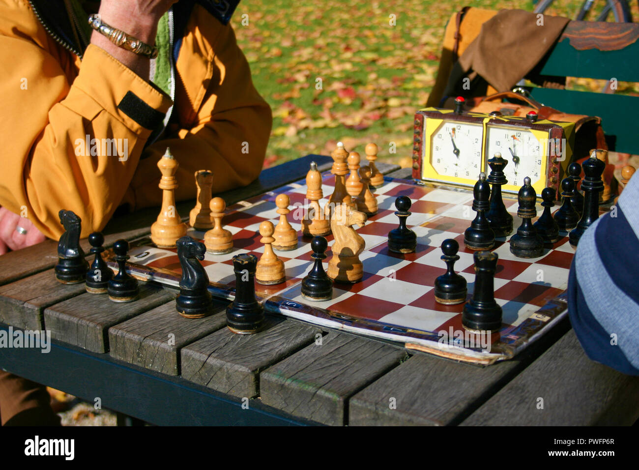 Two men play chess outdoors in a park on a wooden table. Close up. Only hands can be seen Stock Photo