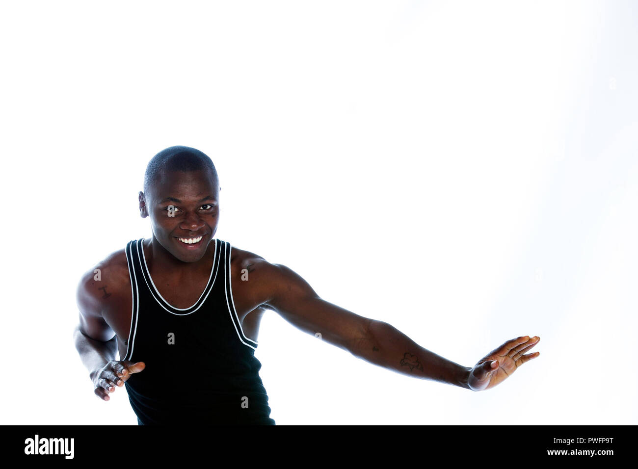 Young handsome african male with prison tatoos and scars wearing a muscle shirt moving and smiling. Stock Photo