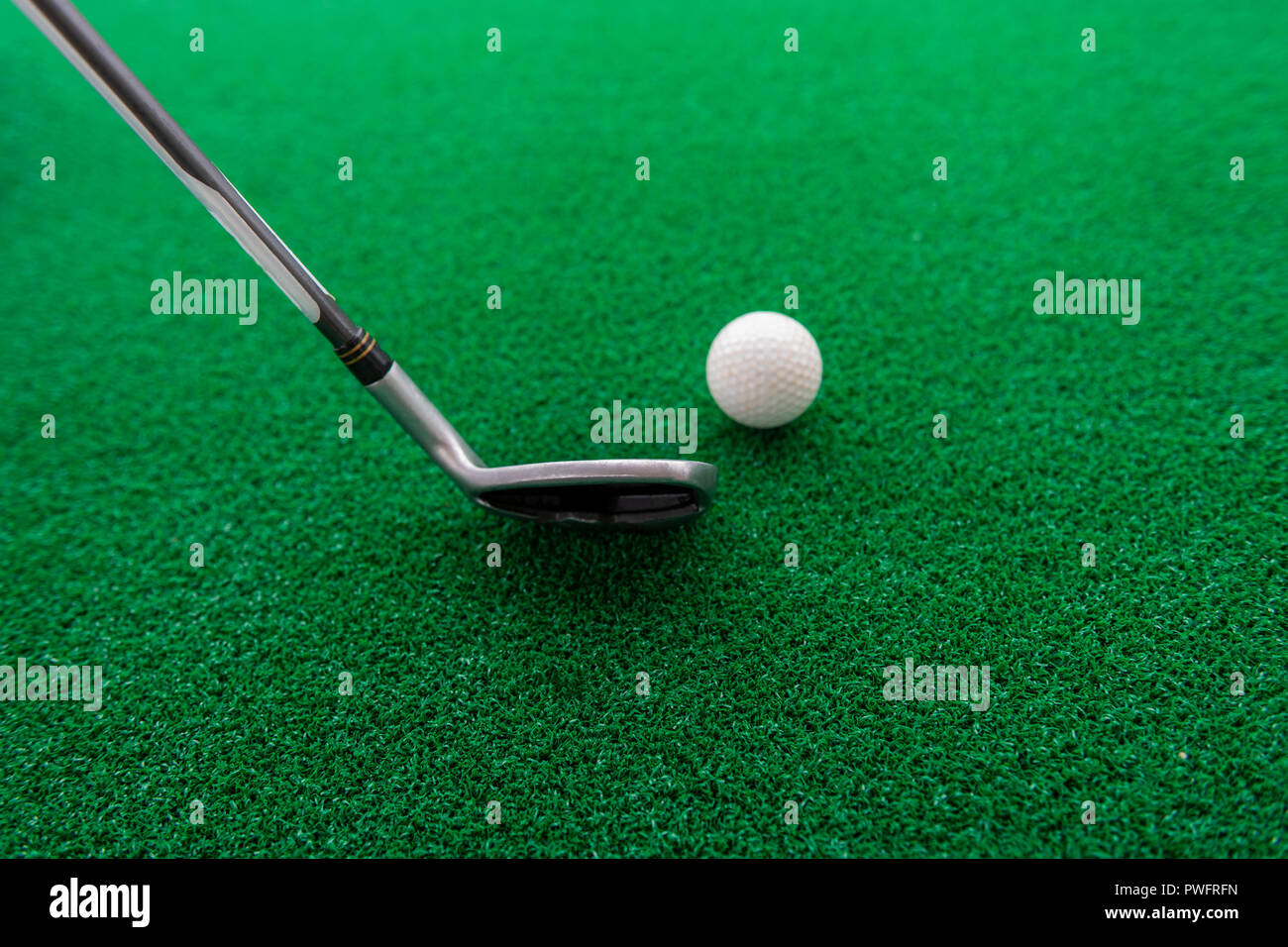 Golf club and ball on a synthetic grass mat at a practice range Stock