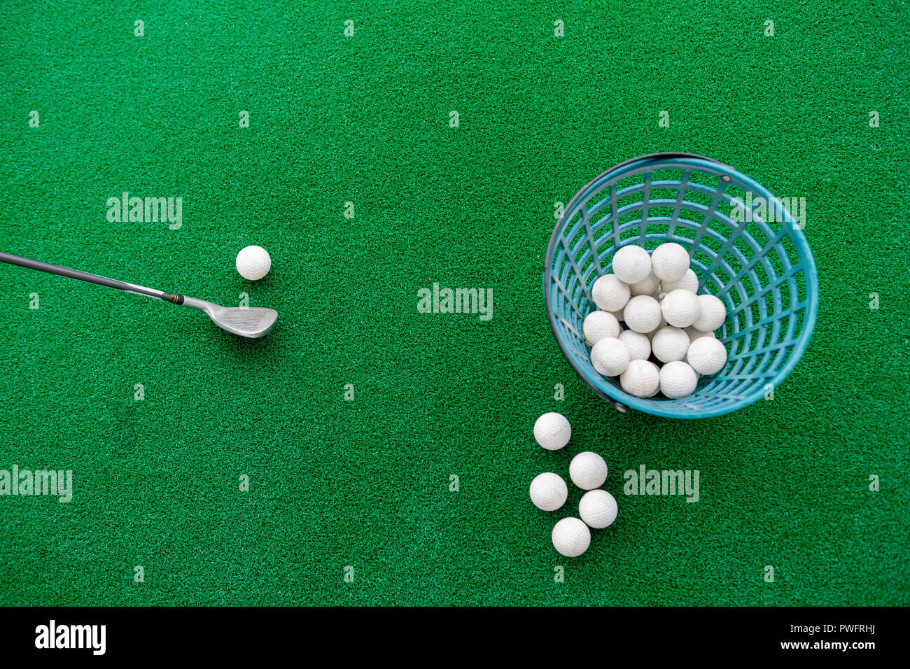 Golf club and balls on a synthetic grass mat at a practice range Stock