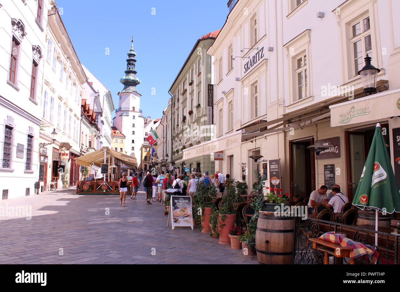 Pedestrians and cafes along Venturska Michalska with view of Michael's Gate in old town of Bratislava, Slovakia Stock Photo