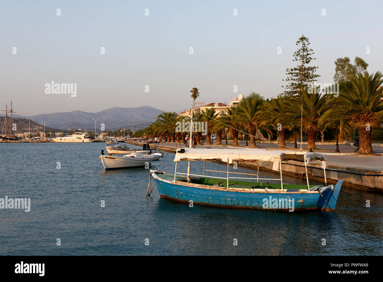 Palm trees line the waterfront and fishing boats dock in the harbour of the town of Nafplio. Peloponnese. Greece. From 1829 to 1334, the town was the  Stock Photo