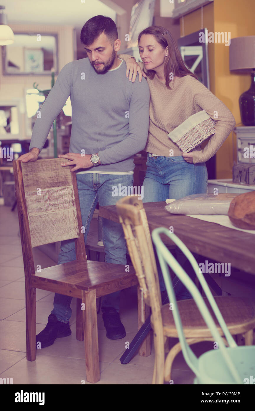 Loving Couple Looking For Wooden Chairs In Shop Of Secondhand