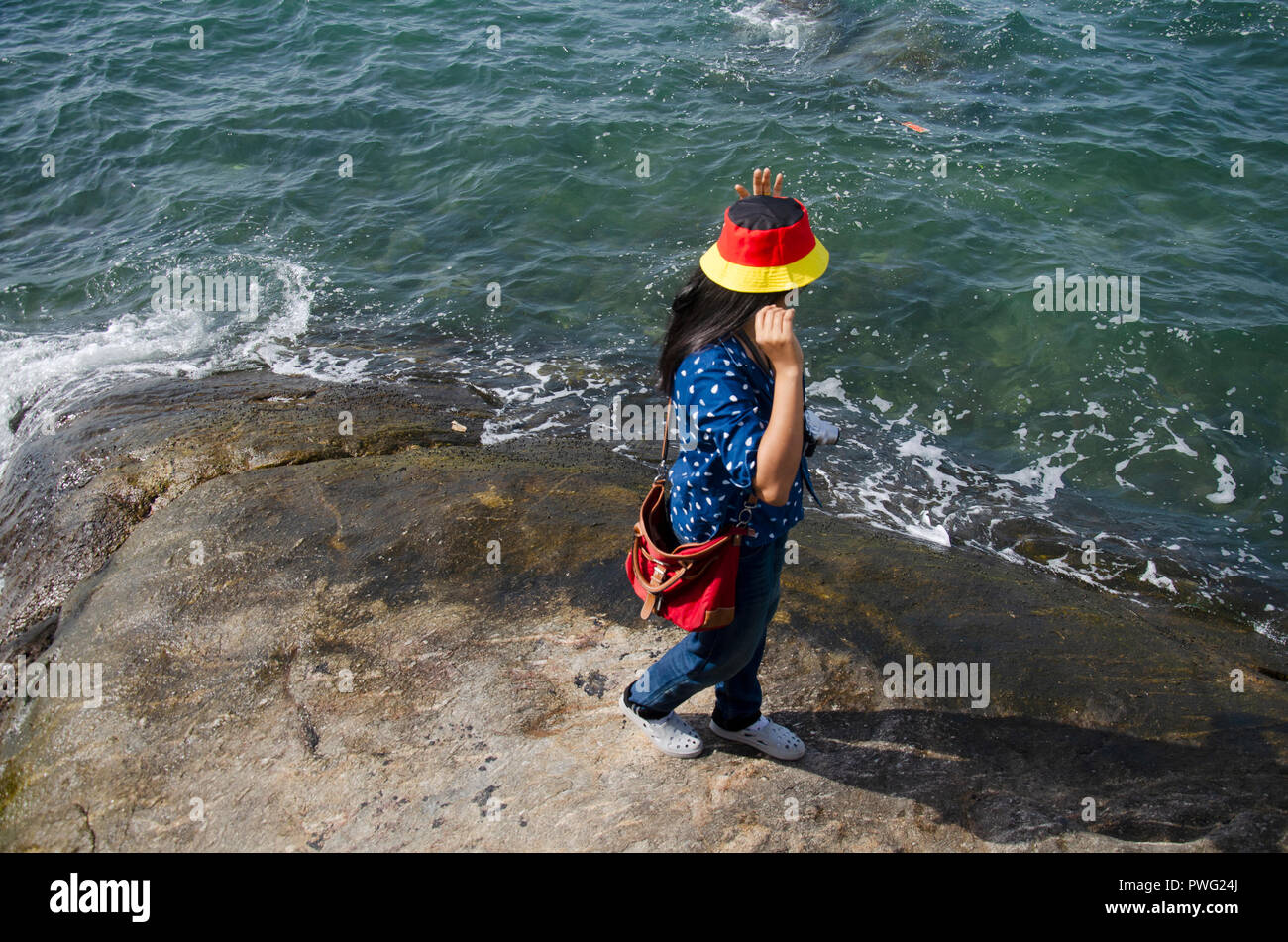 Thai woman people posing for take photo on the rock in the sea at Laem Thaen Cape in Bang Saen Beach in Chonburi, Thailand Stock Photo