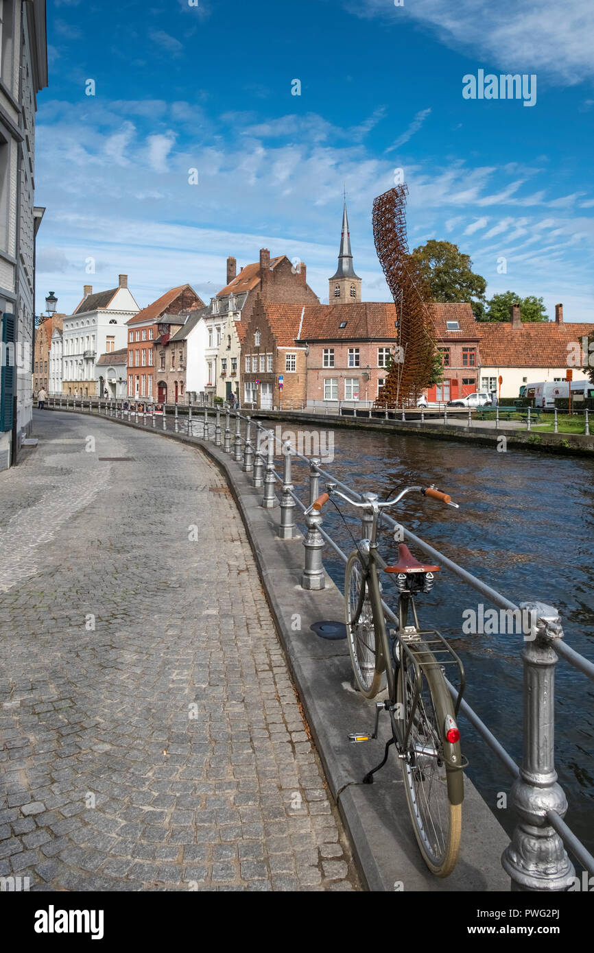 Modern metal street art displayed alongside a canal with traditional architecture in the medieval city of Bruges, West Flanders, Belgium. Stock Photo