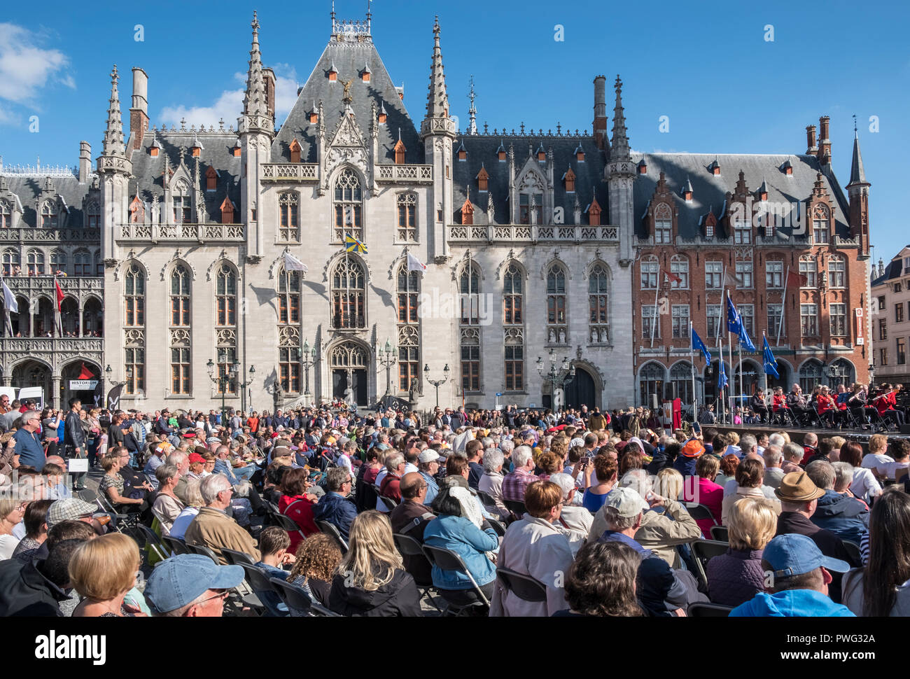 An audience enjoying an open air music concert during a sunny September day in the market square, Markt, Bruges, Flanders, Belgium. Stock Photo