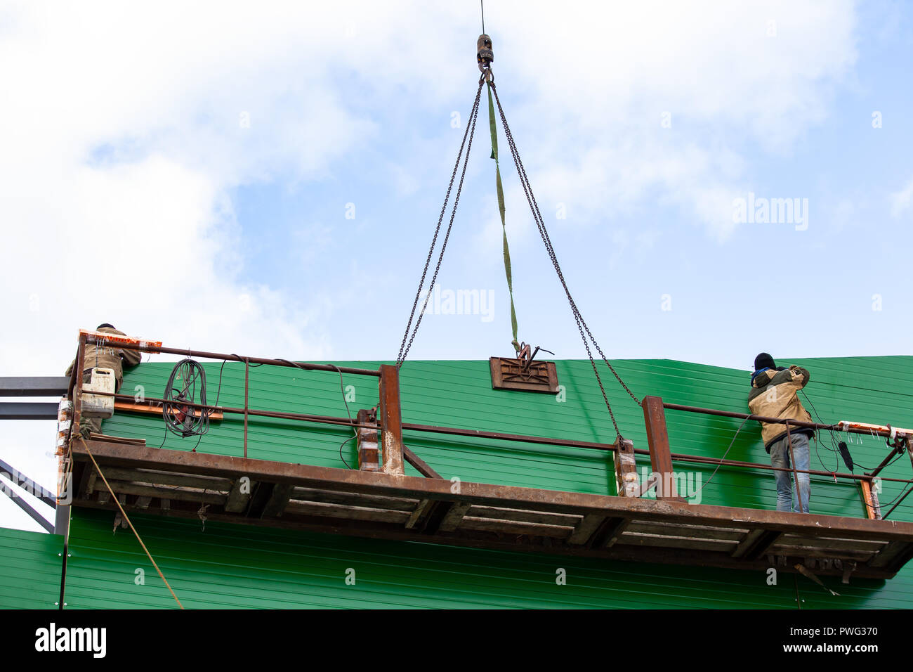 The builders are building a building of metal structures at a height in