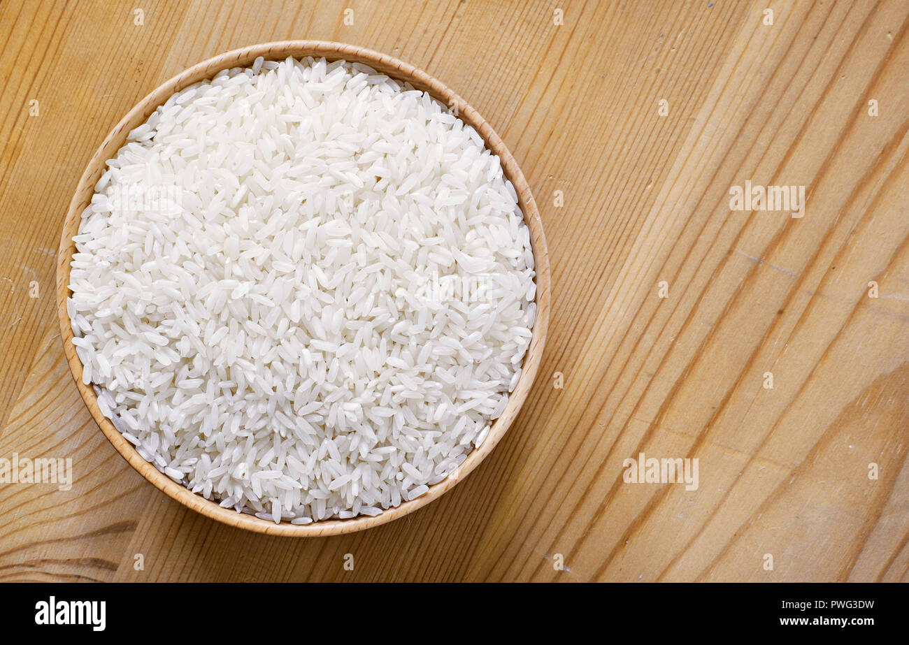 Raw, parboiled rice in a wooden bowl. Rice dish on a wooden table, diet or healthy eating scene. Stock Photo