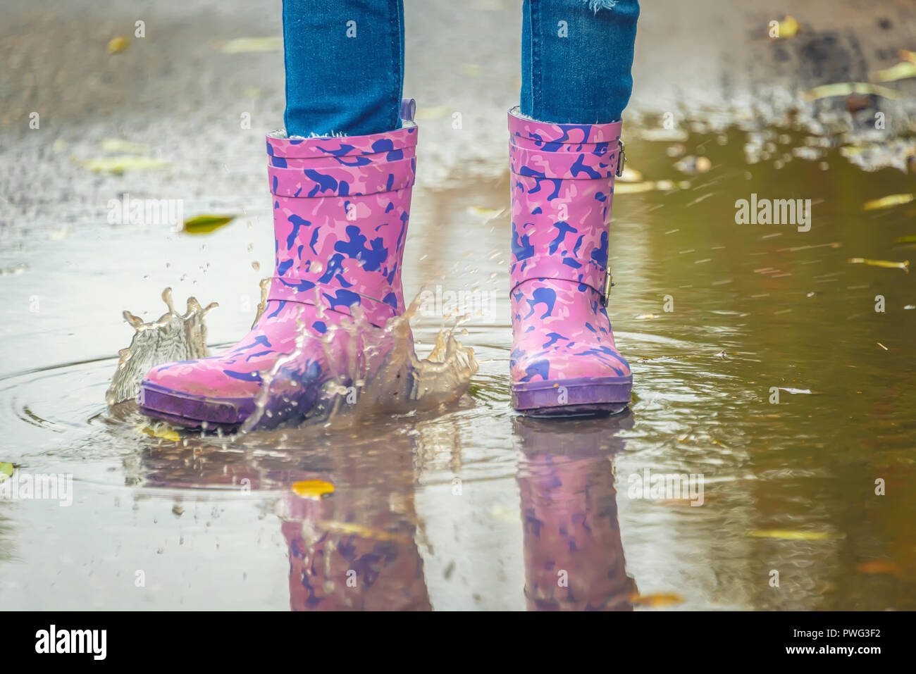 children's feet in rubber boots stand in a puddle in the autumn Stock ...