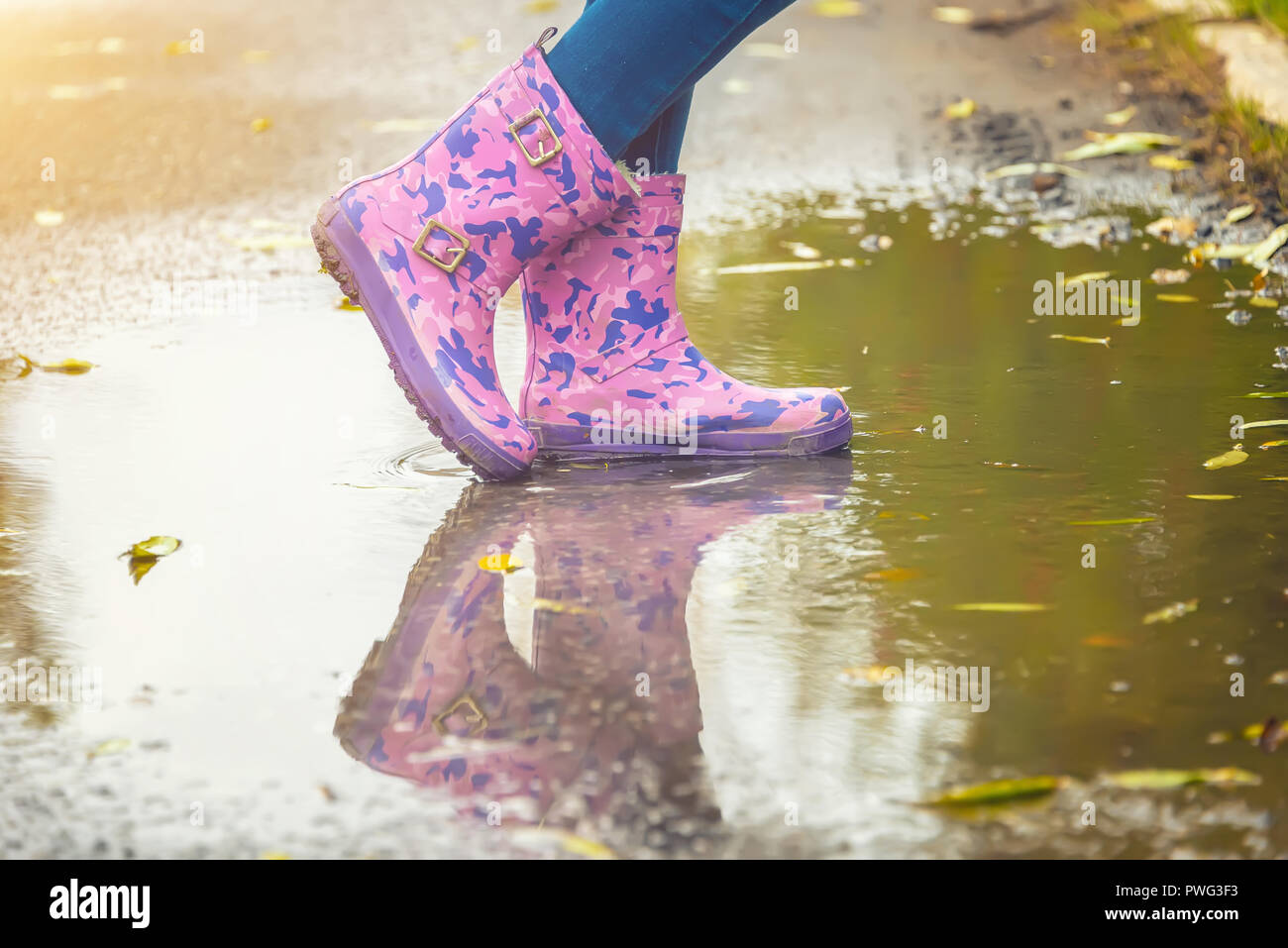 children's feet in rubber boots stand in a puddle in the autumn Stock ...