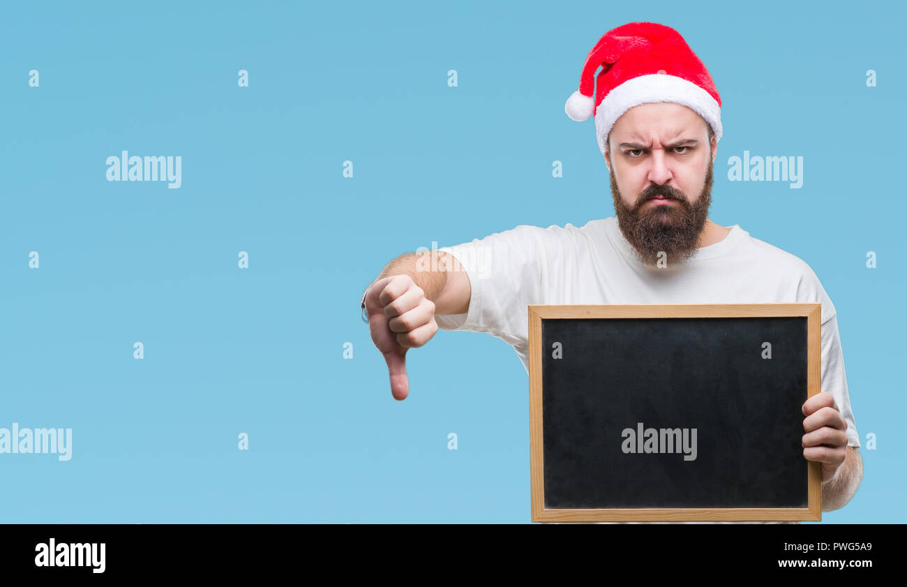 Young caucasian hipster man wearing christmas hat holding blackboard ...
