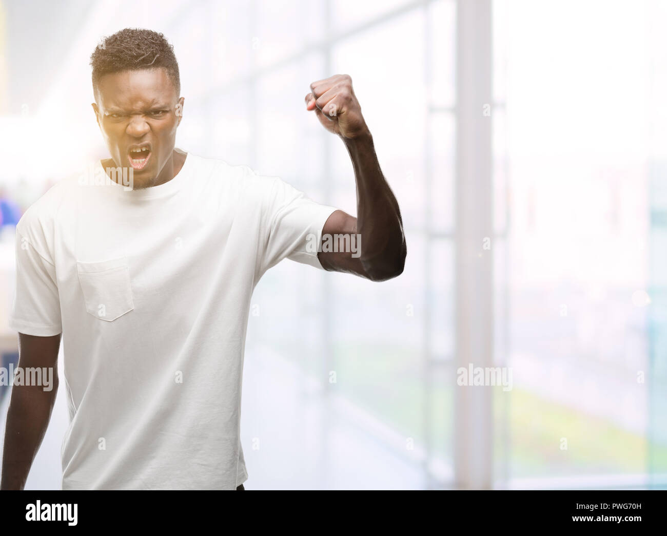 Young african american man wearing white t-shirt angry and mad raising ...