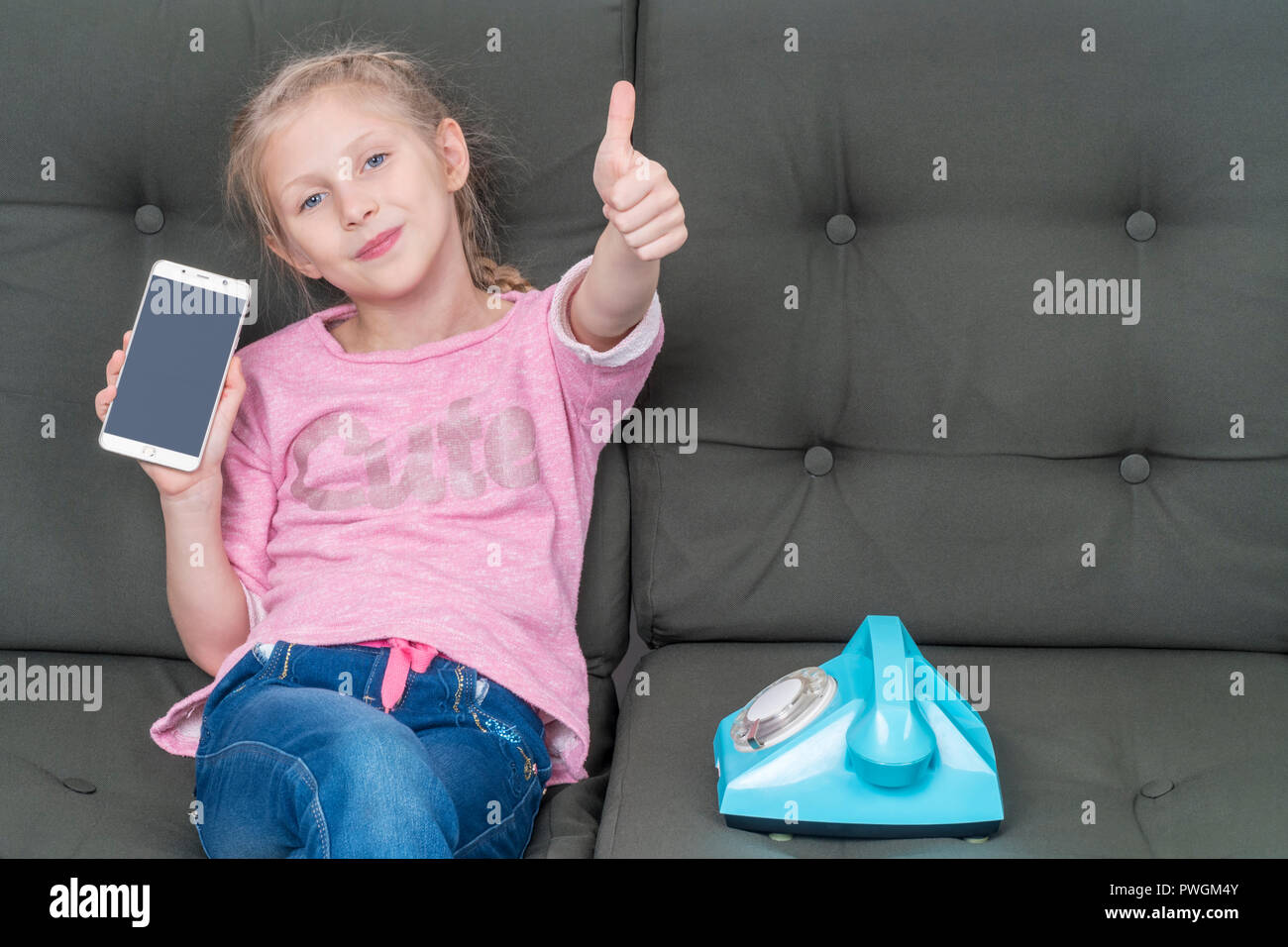 girl sitting on the couch next to a retro phone shows the screen of her