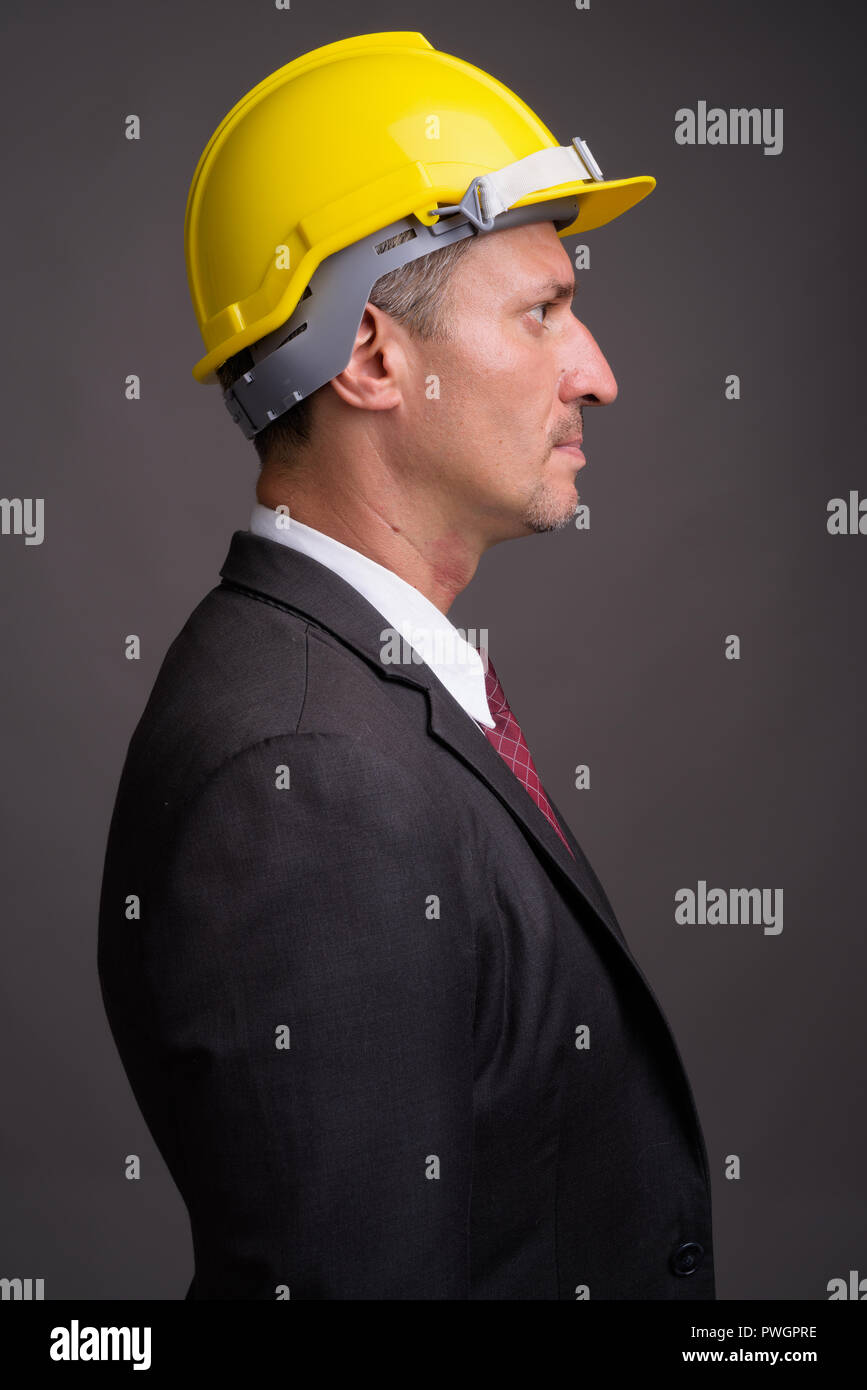 Portrait of businessman with hardhat against gray background Stock Photo