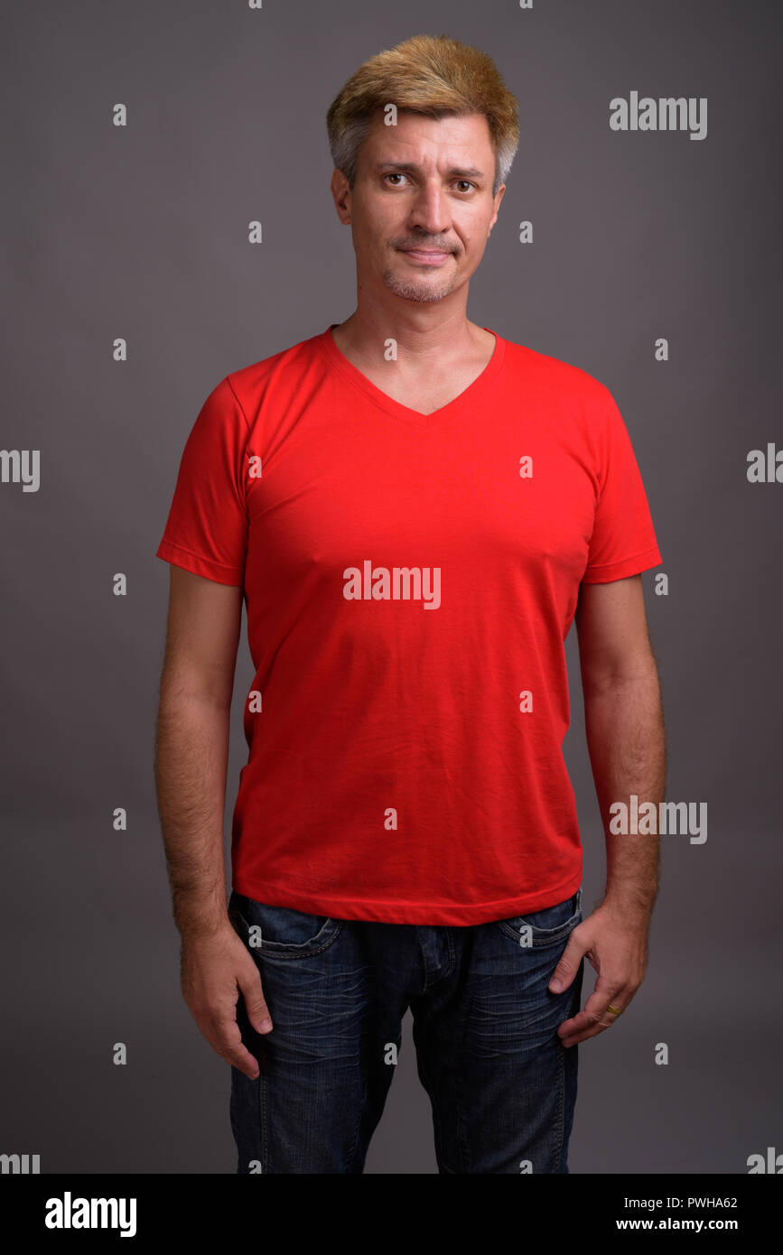 Man with blond hair wearing red shirt against gray background Stock Photo