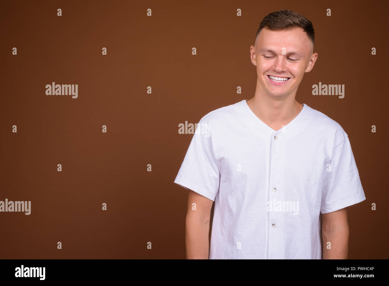 Young man wearing white shirt against brown background Stock Photo