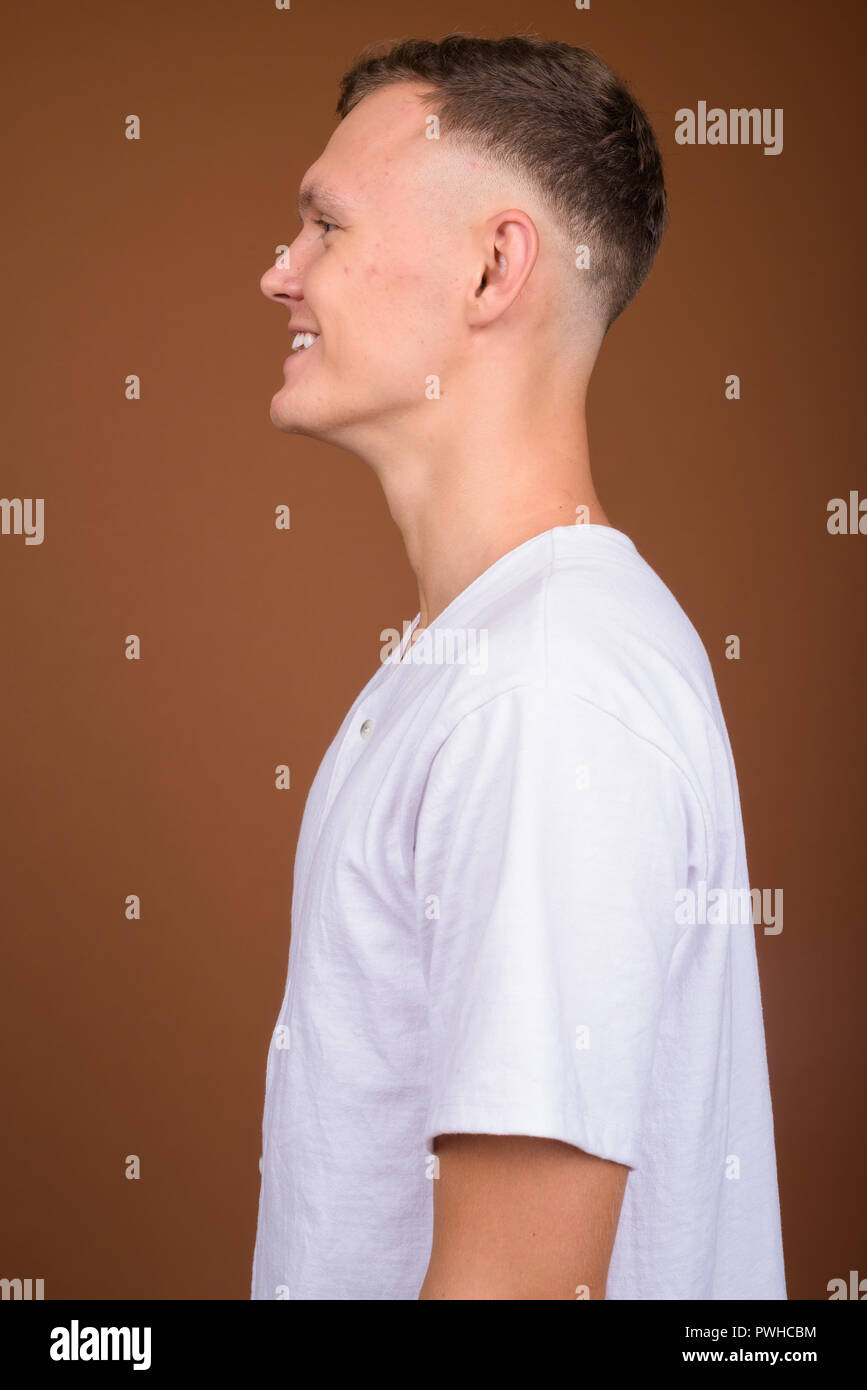 Young man wearing white shirt against brown background Stock Photo